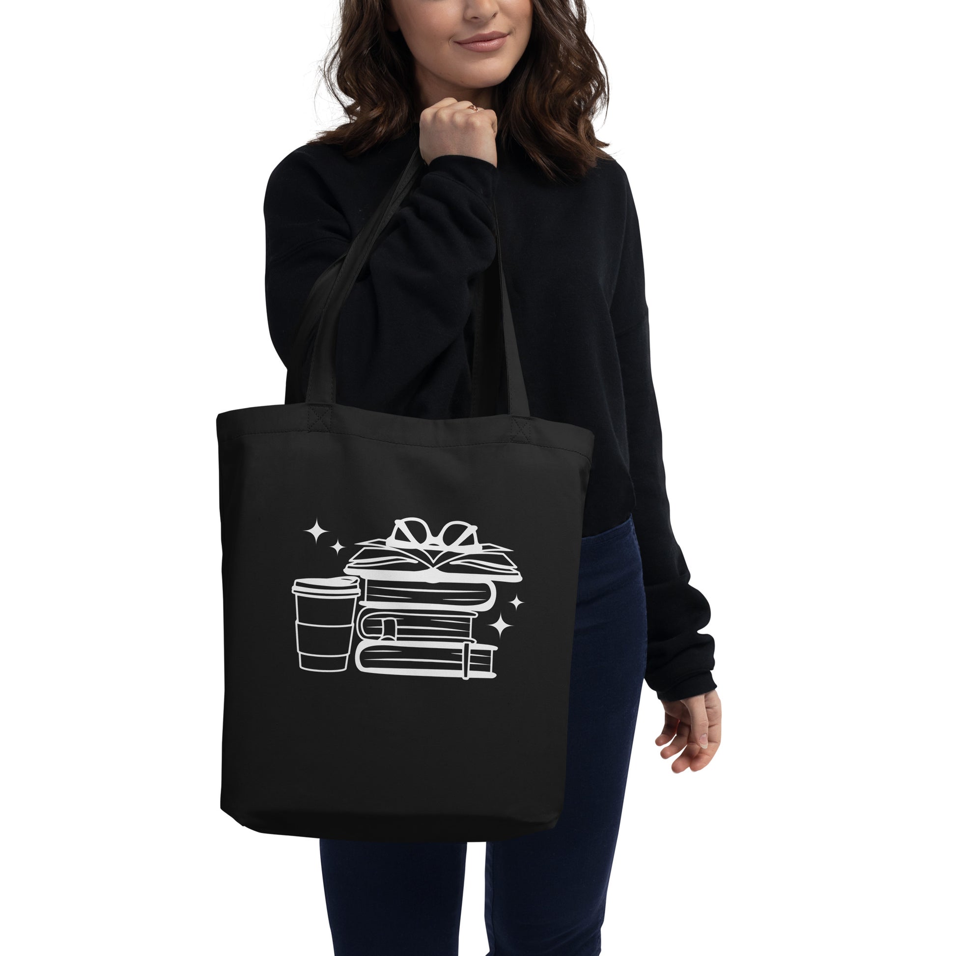 Woman holding Black cotton tote bag featuring stack of books with glasses on top with coffee cup. Perfect book bag for book lovers