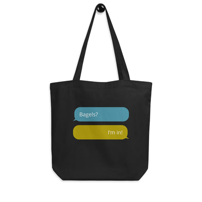 Black cotton tote back with graphic to look like text messages words say: Bagels? The reply messages says "I'm in: