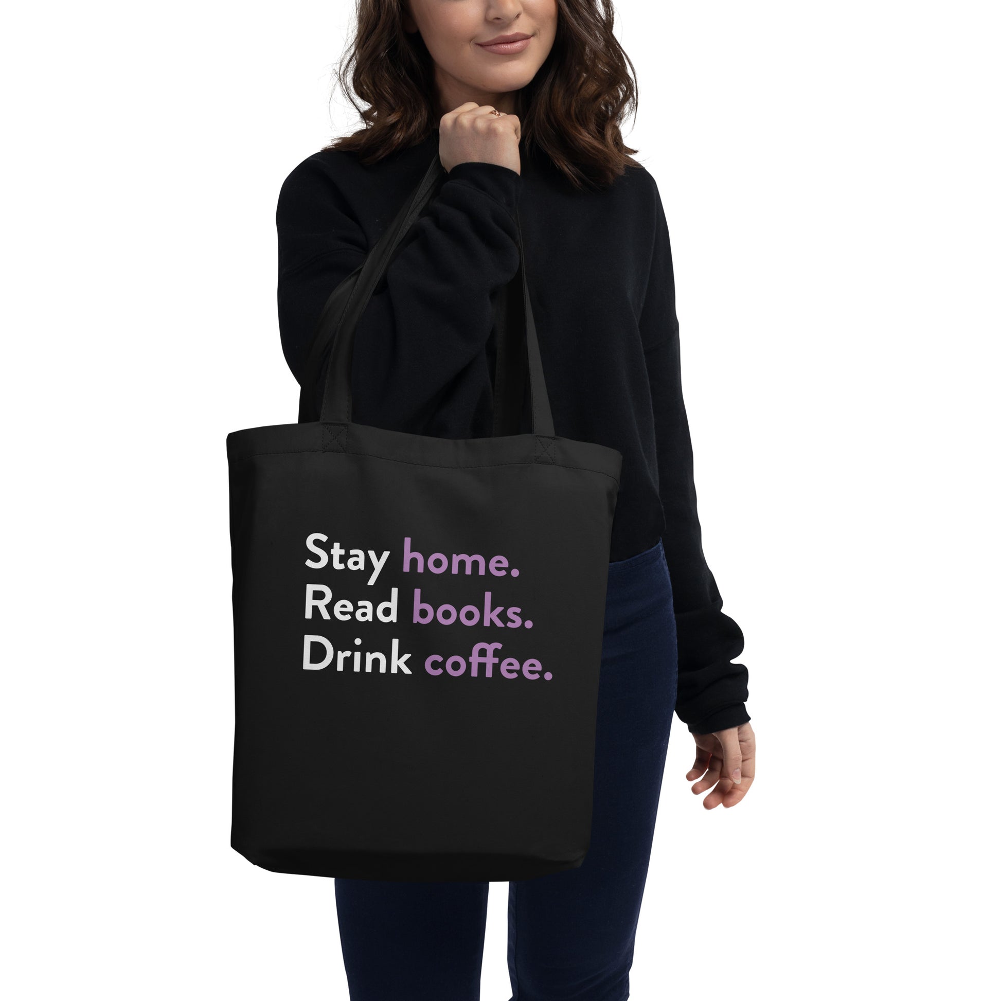 Woman holding black tote bag that says Stay home, read books, drink coffee
